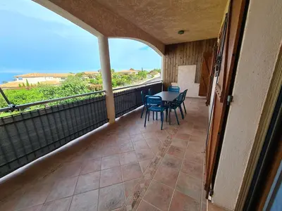 a balcony with a table and chairs and a view of the ocean at Les Terrasses de Sari in Sari Solenzara