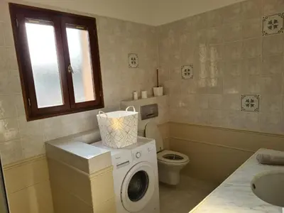 a bathroom with a washing machine and a toilet at Les Terrasses de Sari in Sari Solenzara