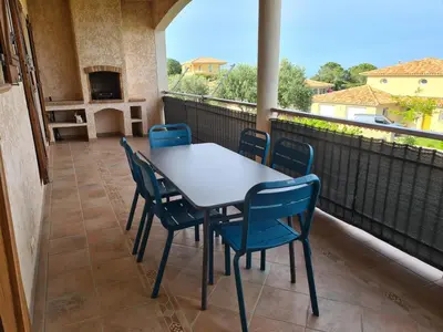 a patio with a table and chairs on a balcony at Les Terrasses de Sari in Sari Solenzara