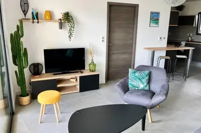 a living room with a tv and a chair and a table at Appartement magnifique - Luxe - Proche du port - 1 chambre - Pour des vacances paisibles in Porto-Vecchio