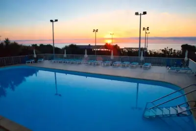 a large swimming pool with a sunset in the background at Studio charmant à Cervione avec piscine partagée - 30 m² in Cervione
