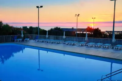 a pool with chairs and a sunset in the background at Studio charmant à Cervione avec piscine partagée - 30 m² in Cervione