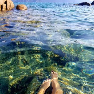 a woman laying in the water with her feet in the water at Appartement T2bis Sartène 60m2 avec jolie terrasse de 25m2 et vue panoramique mer et montagne sur le Golfe du Valinco - Quartier calme à 10mn à pied du centre ville - Idéal pour 4 personnes et possibilité de 6 couchages - Place de parking réservée in Sartène