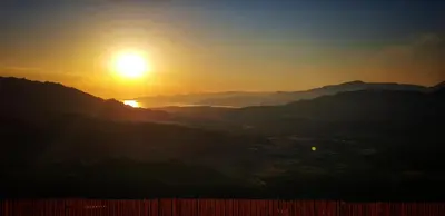 a sunset in the mountains with the sun in the sky at Appartement T2bis Sartène 60m2 avec jolie terrasse de 25m2 et vue panoramique mer et montagne sur le Golfe du Valinco - Quartier calme à 10mn à pied du centre ville - Idéal pour 4 personnes et possibilité de 6 couchages - Place de parking réservée in Sartène