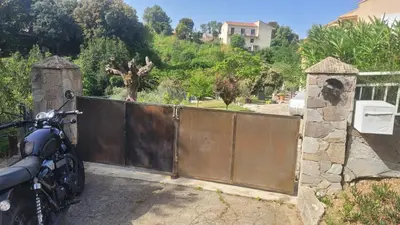 a motorcycle parked in front of a gate at F2 rez de jardin in Ajaccio
