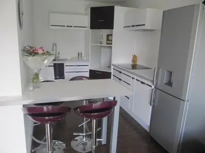 a kitchen with white appliances and purple bar stools at F2 rez de jardin in Ajaccio