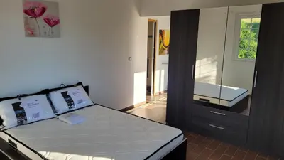 a bedroom with a bed and a dresser with a mirror at F2 rez de jardin in Ajaccio