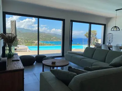 a living room with a couch and a view of the ocean at Villa Pura Corsica with sea view and private pool in Conca
