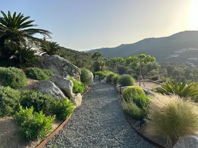 a garden with rocks and plants on a hill at Villa Pura Corsica with sea view and private pool in Conca