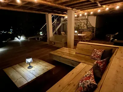 a porch with a bench and a table and a lamp at Villa Pura Corsica with sea view and private pool in Conca