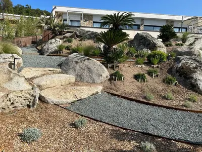 a garden with rocks and plants in front of a building at Villa Pura Corsica with sea view and private pool in Conca