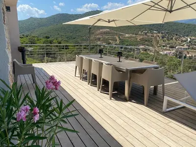 a wooden deck with a table and chairs and an umbrella at Villa Pura Corsica with sea view and private pool in Conca
