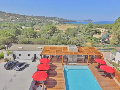 a house with a swimming pool with red umbrellas at STUDIO PORTICCIO AGOSTA PLAGE in Porticcio
