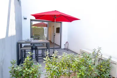 a patio with a table and a red umbrella at STUDIO PORTICCIO AGOSTA PLAGE in Porticcio