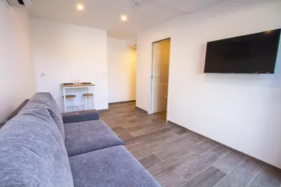 a living room with a couch and a flat screen tv at STUDIO PORTICCIO AGOSTA PLAGE in Porticcio