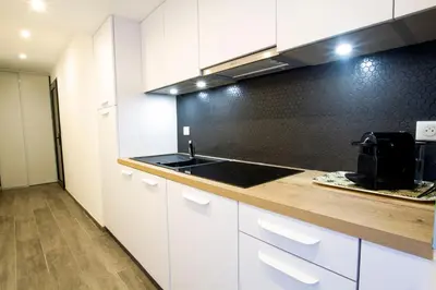 a kitchen with white cabinets and a black wall at STUDIO PORTICCIO AGOSTA PLAGE in Porticcio
