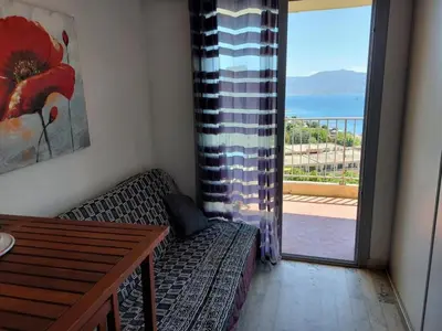 a living room with a couch and a table and a balcony at AJACCIO VUE IMPRENABLE APPT 3 P POUR 4 OU 5 PERSONNES SANGUINAIRES 300M PLAGES ET MERPERSONNES in Ajaccio