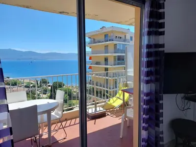a balcony with a view of a building and the ocean at AJACCIO VUE IMPRENABLE APPT 3 P POUR 4 OU 5 PERSONNES SANGUINAIRES 300M PLAGES ET MERPERSONNES in Ajaccio