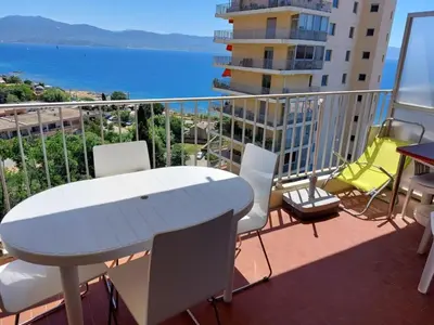 a balcony with a white table and chairs and the ocean at AJACCIO SANGUINAIRES APPT 3P POUR 4 A 5 P TTES COMMODITÉS TT CONFORT A 300M DE LA MER ET A 5 MN DU CENTRE VILLE in Ajaccio