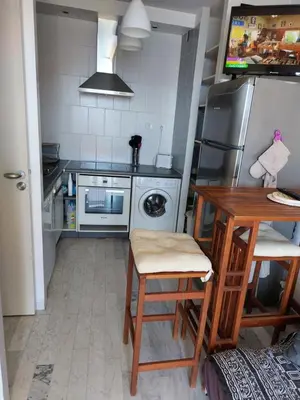a kitchen with a table and a refrigerator at AJACCIO SANGUINAIRES APPT 3P POUR 4 A 5 P TTES COMMODITÉS TT CONFORT A 300M DE LA MER ET A 5 MN DU CENTRE VILLE in Ajaccio