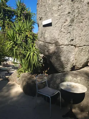 a chair and a table in front of a large rock at CAMPING GALLINA VARJA in Sotta