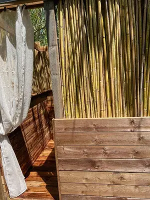 a stack of bamboo standing next to a wooden fence at CAMPING GALLINA VARJA in Sotta