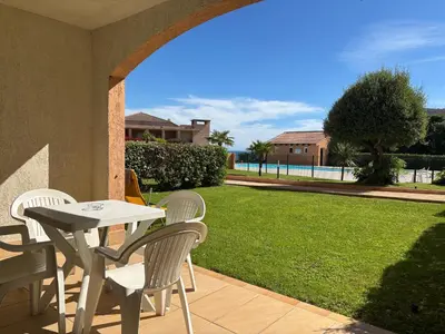 a table and chairs on a patio with a lawn at PALMERAIE 218 in Sari Solenzara