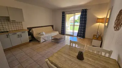 a kitchen and a living room with a table and a couch at PALMERAIE 218 in Sari Solenzara