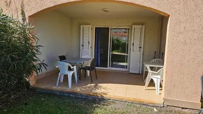 a patio with a table and chairs on a porch at PALMERAIE 218 in Sari Solenzara