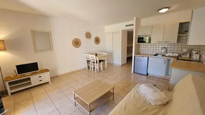 a kitchen and a living room with a table at PALMERAIE 218 in Sari Solenzara