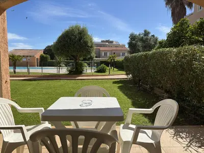 a white table and chairs sitting on a lawn at PALMERAIE 218 in Sari Solenzara