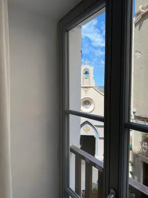 a window view of a church with a clock tower at Entre Ciel et Mer hotel in Bonifacio