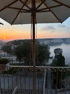 a view of a river from a balcony with an umbrella at Entre Ciel et Mer hotel in Bonifacio