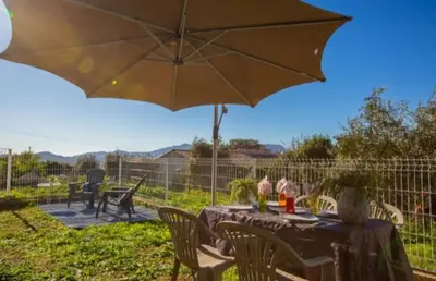 a table with an umbrella in a yard at Logement calme et agréable à proximité d'Ajaccio in Canale