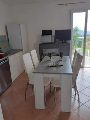 a kitchen with a white table and chairs in a room at Logement calme et agréable à proximité d'Ajaccio in Canale