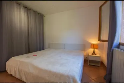 a bedroom with a large white bed and a lamp at Logement calme et agréable à proximité d'Ajaccio in Canale