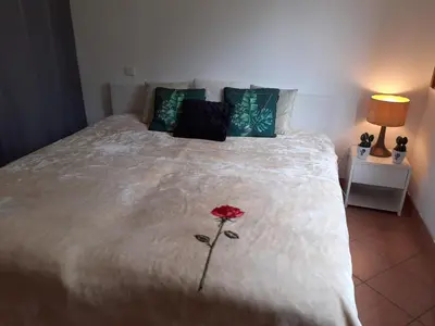 a red flower on a bed with a white blanket at Logement calme et agréable à proximité d'Ajaccio in Canale