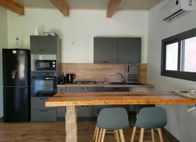 a kitchen with a wooden table and a black refrigerator at Mini Villa Giuseppina in Bonifacio