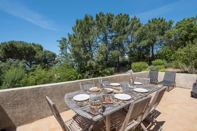 a wooden table and chairs on a patio at La Pinède - Maison proche plages in Pietrosella