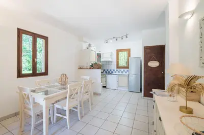 a white kitchen with a white table and chairs at La Pinède - Maison proche plages in Pietrosella