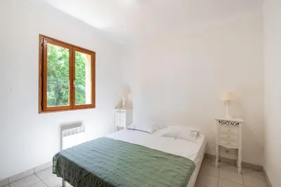 a white bedroom with a bed and a window at La Pinède - Maison proche plages in Pietrosella