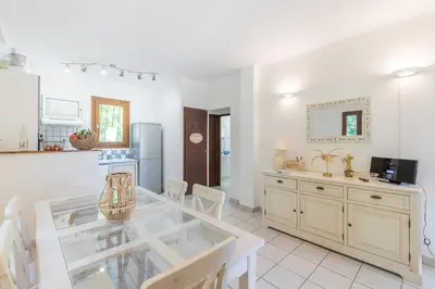 a dining room with a glass table and a kitchen at La Pinède - Maison proche plages in Pietrosella