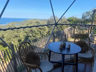 a table and chairs on a balcony with a view of the ocean at Domaine de Sonia - Logements éco-insolites in Porto-Vecchio