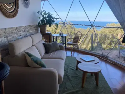 a living room with a couch and a large window at Domaine de Sonia - Logements éco-insolites in Porto-Vecchio