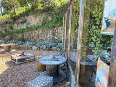 a patio with a table and benches and a wall at Domaine de Sonia - Logements éco-insolites in Porto-Vecchio