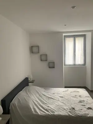 a bed in a white room with a window at Au cœur de sartene in Sartène