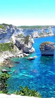 a large body of blue water with large rocks at Spacieux T3 Proche Port de Porto Vecchio in Porto-Vecchio