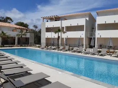 a swimming pool with lounge chairs in front of a building at Studio les pieds dans l'eau vue sur mer in Linguizzetta