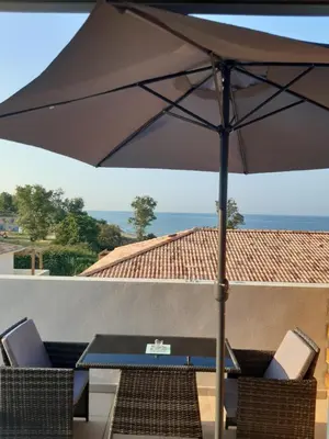 a table and chairs with an umbrella on a patio at Studio les pieds dans l'eau vue sur mer in Linguizzetta