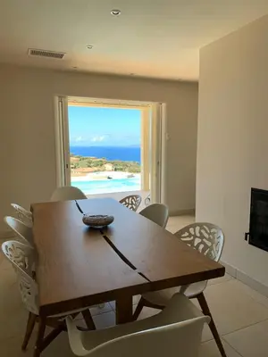 a dining room table and chairs with a view of the ocean at Maison vue mer Propriano Viggianello in Viggianello